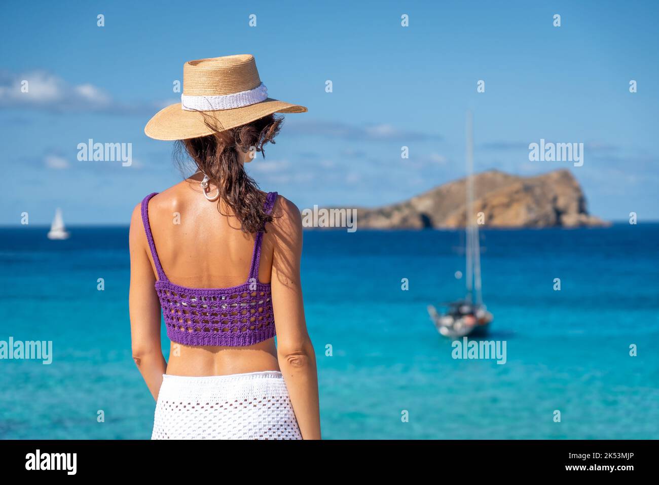 Femme Brunette avec chapeau, jupe blanche et haut violet sur les rives de la Méditerranée Banque D'Images