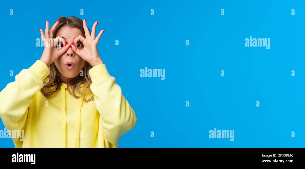 Impressionnée et intriguée, curieuse jeune fille caucasienne dans le sweat à capuche jaune regardant quelque chose d'impressionnant, trouvé grand produit spécial rabais, faire Banque D'Images