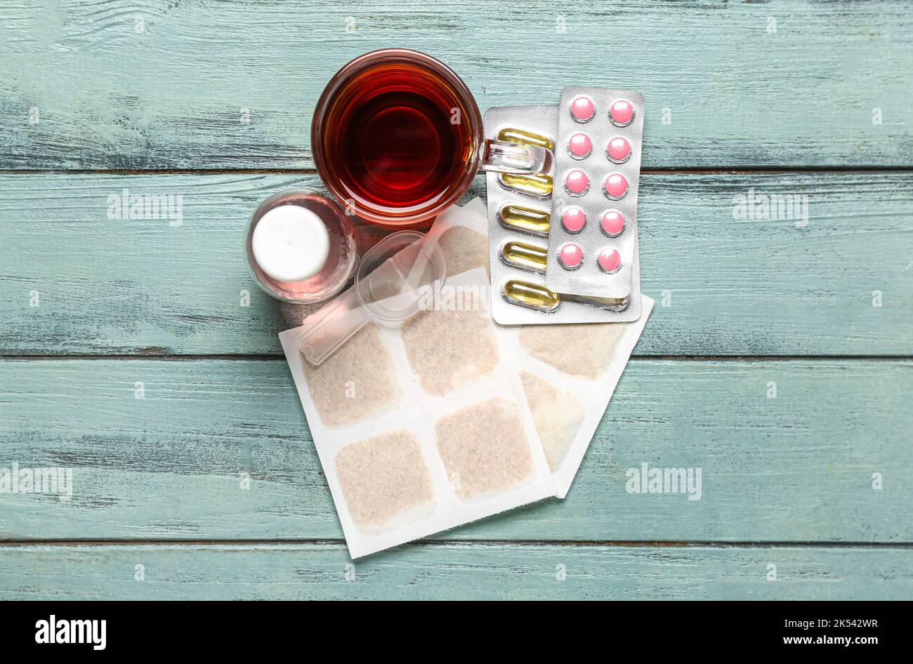 Emplâtres à la moutarde avec une tasse de thé, des pilules et du sirop contre la toux sur fond de bois de couleur Banque D'Images