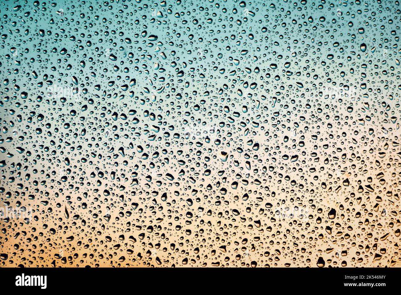 Fenêtre humide fond orange sarcelle, gouttes d'eau sur le verre, temps pluvieux, espace de copie Banque D'Images