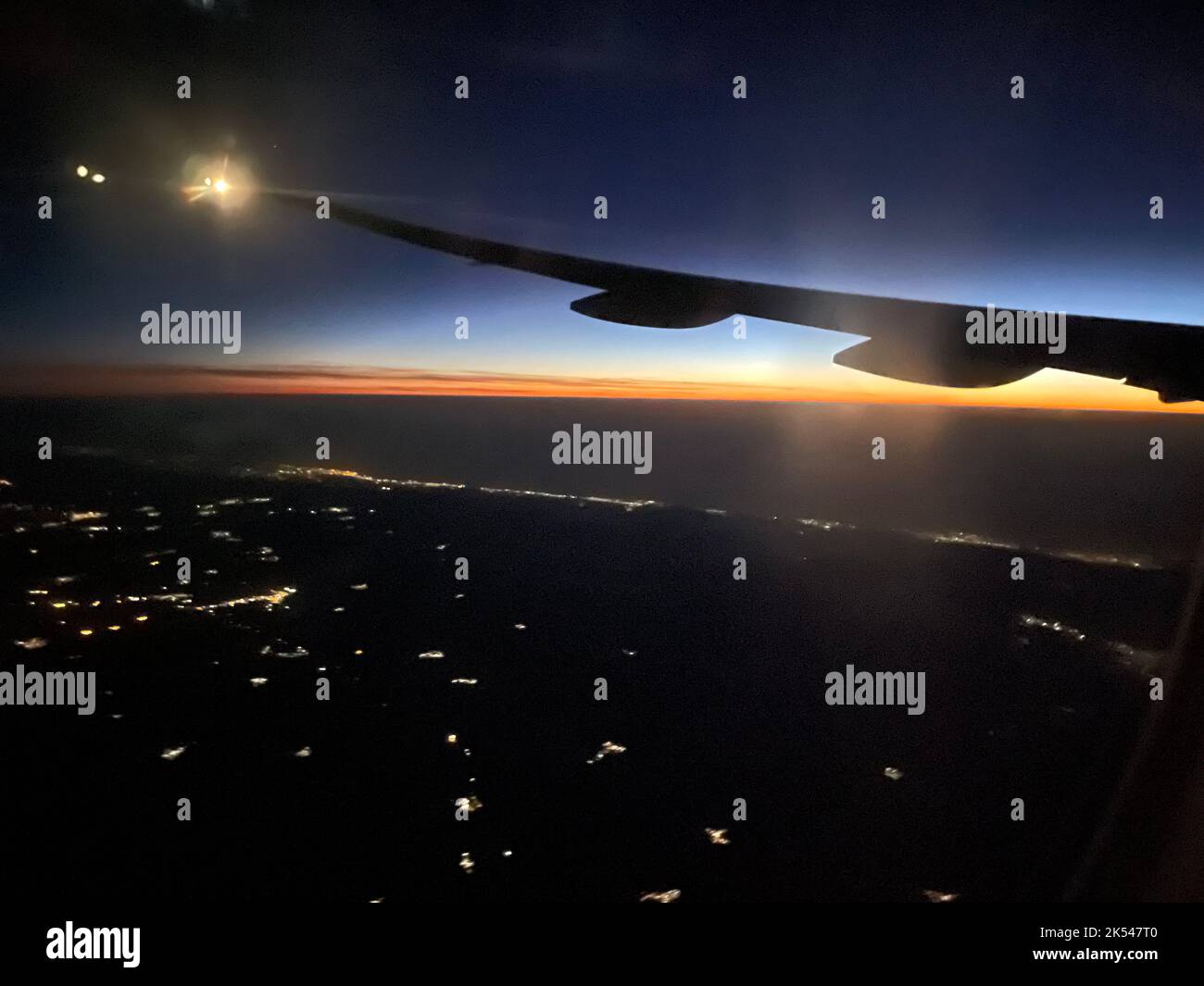 Silhouette de l'aile de l'avion dans le ciel de nuit avec lever du soleil au loin Banque D'Images