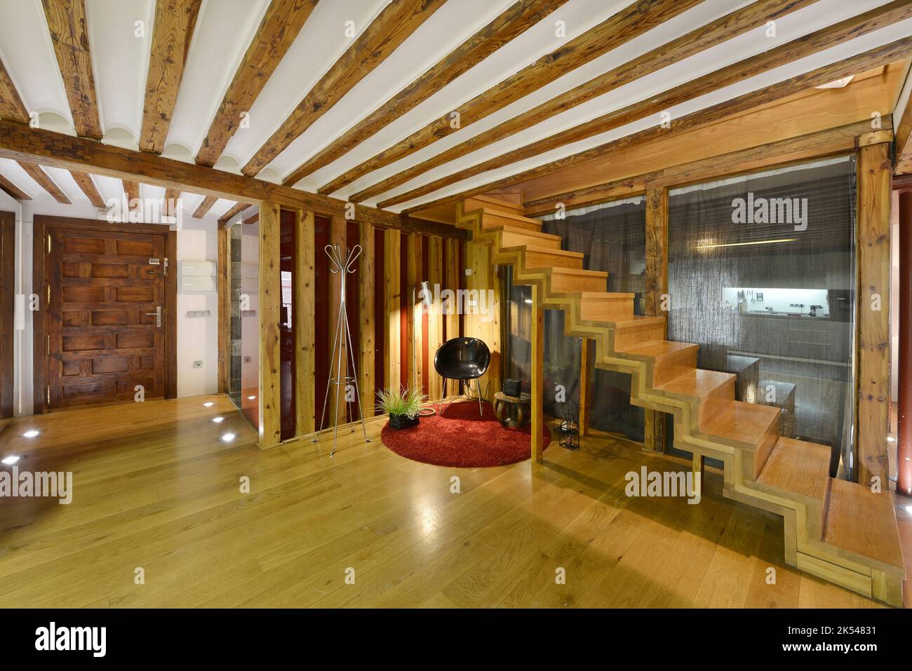 Salon avec escalier en bois dans une maison en duplex avec porte avant lambrissée en bois Banque D'Images