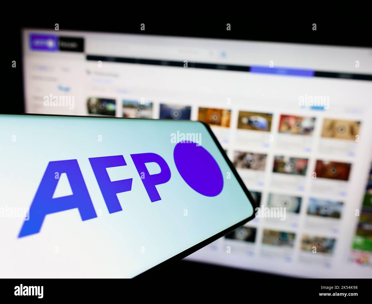 Téléphone portable avec logo de l'agence de presse Agence France-presse (AFP) à l'écran en face du site web des entreprises. Effectuez la mise au point au centre-droit de l'écran du téléphone. Banque D'Images