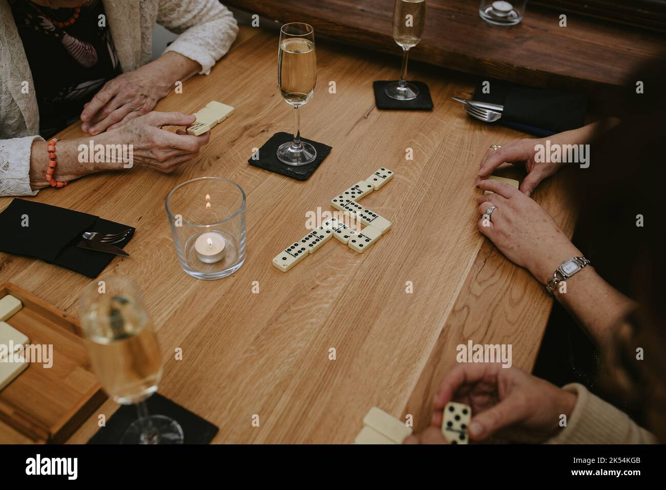 Activités de loisirs, jeu de Domino. Mains de femme âgée jouant des dominos à la table. Les personnes âgées s'amusent avec du vin au café Banque D'Images