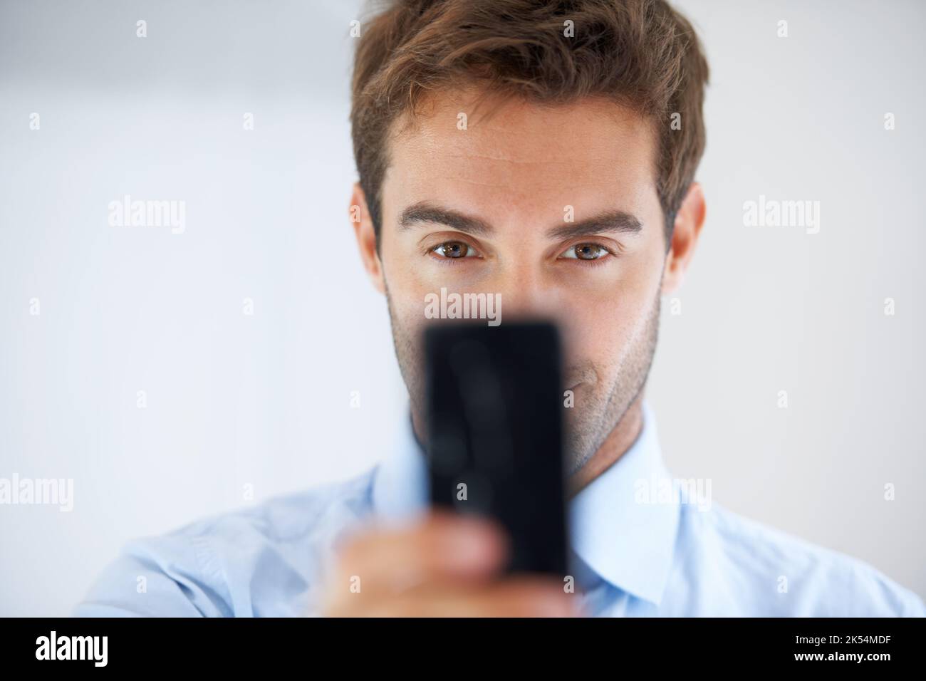Obtenir le cadre parfait. Un homme d'affaires tenant son téléphone pour prendre une photo. Banque D'Images