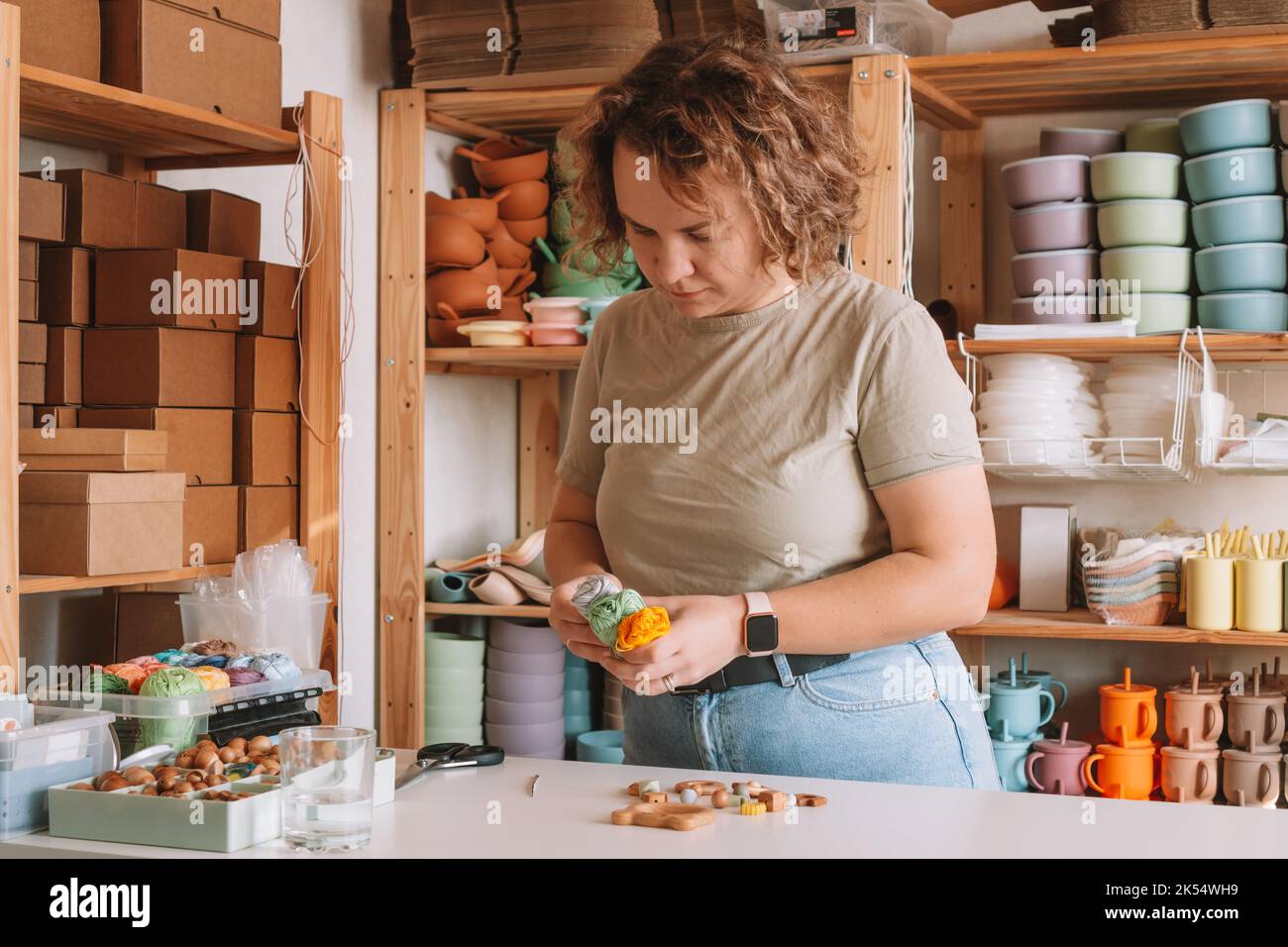 Femme en bois naturel sûr sur le bureau, style écologique. Perles de cerclées. Jouet de dentition avec décoration de ferraillement de cercueil. Travail de fabrication à la main de Banque D'Images