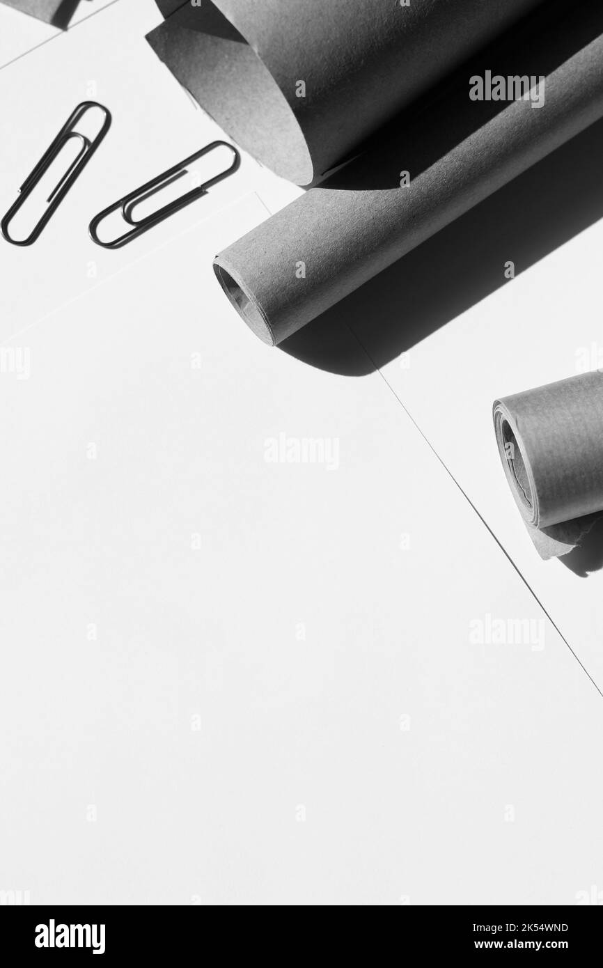 Maquette d'entreprise monochrome. Rouleaux de papier, feuilles de papier avec trombones disposés sur le bureau de White Office. Banque D'Images