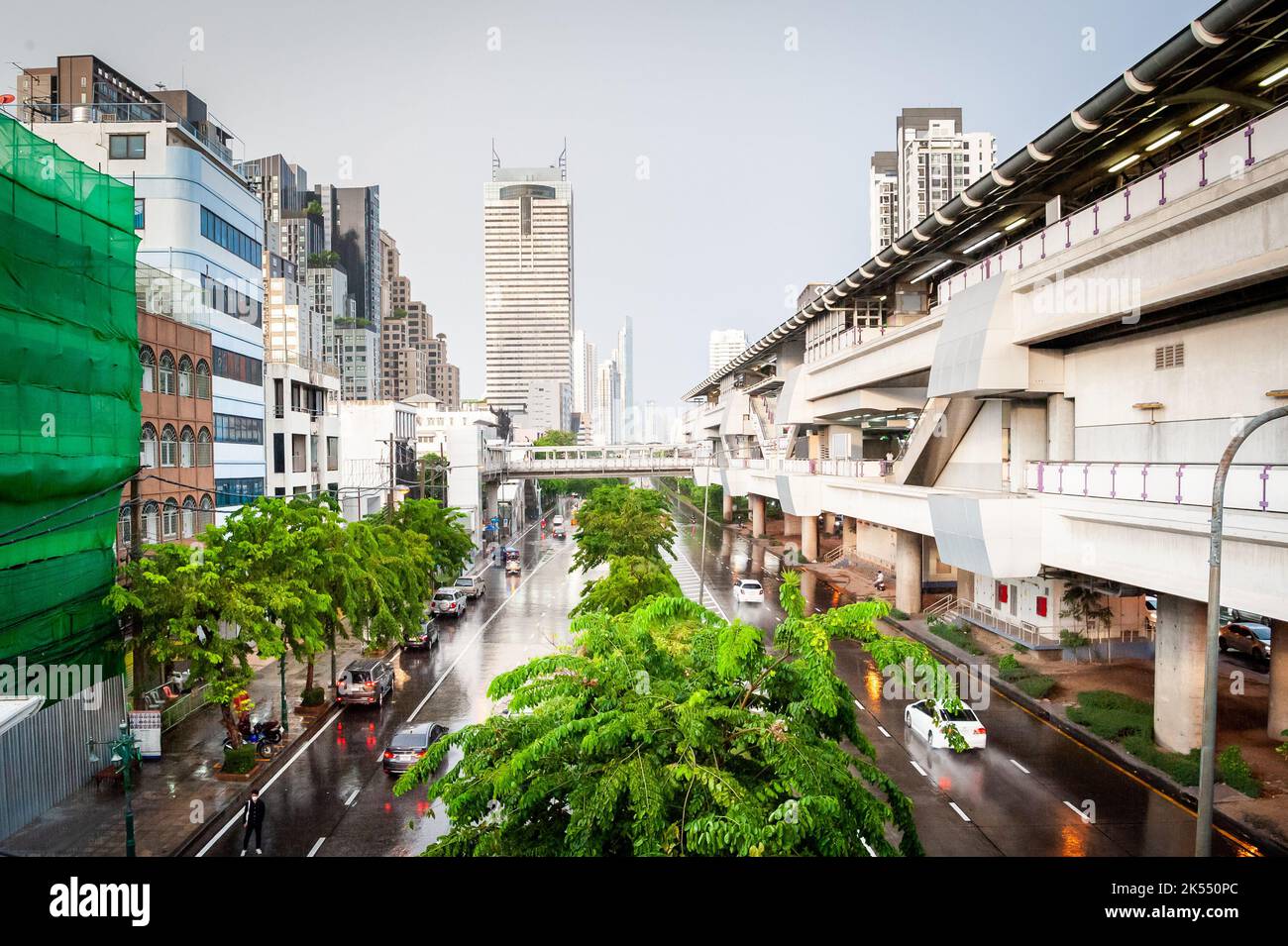 Vue sur une route principale dans le centre de Bangkok, en Thaïlande par un jour pluvieux montrant le train aérien à droite. Banque D'Images