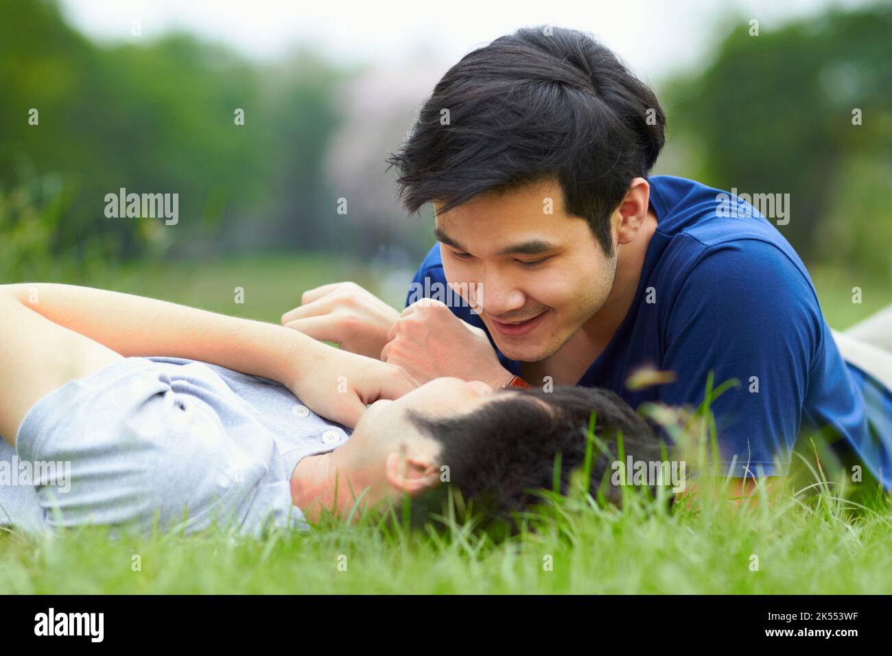 Partager un moment. Un jeune couple gay affectueux allongé sur l'herbe ensemble. Banque D'Images