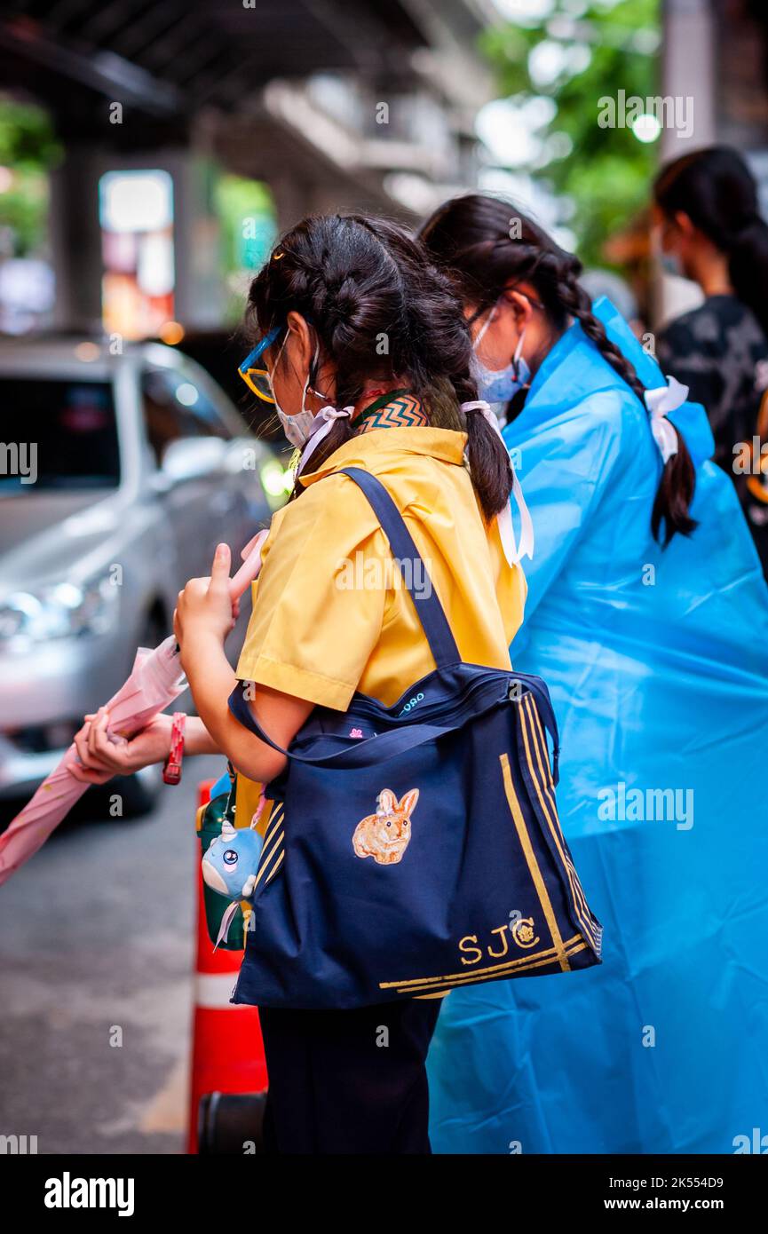 Une jeune fille d'école thaïlandaise portant un masque Covid attend le bus scolaire à Sala Daeng, Bangkok, Thaïlande. Banque D'Images