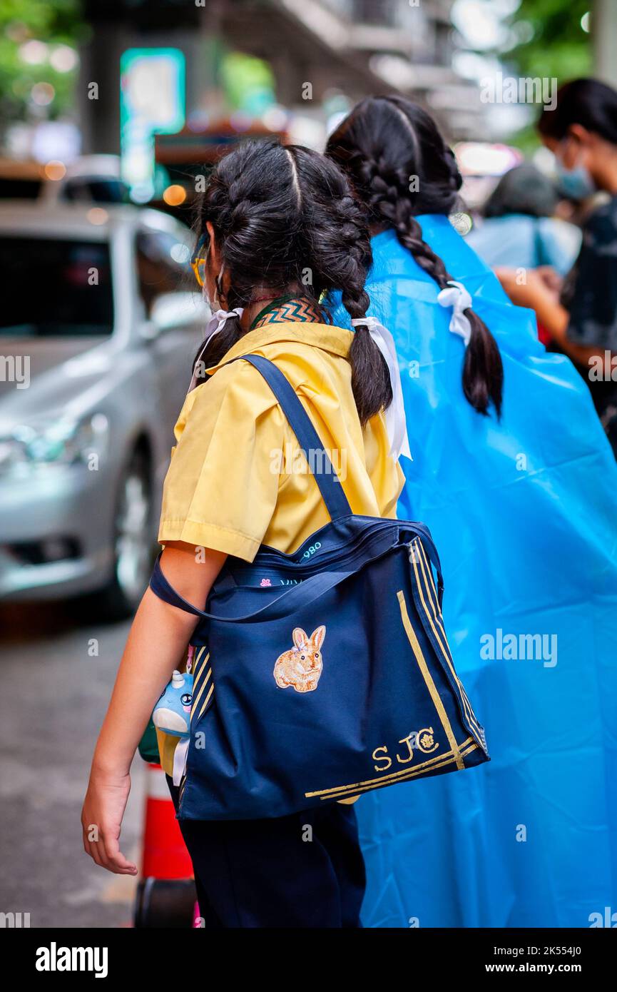 Une jeune fille d'école thaïlandaise portant un masque Covid attend le bus scolaire à Sala Daeng, Bangkok, Thaïlande. Banque D'Images