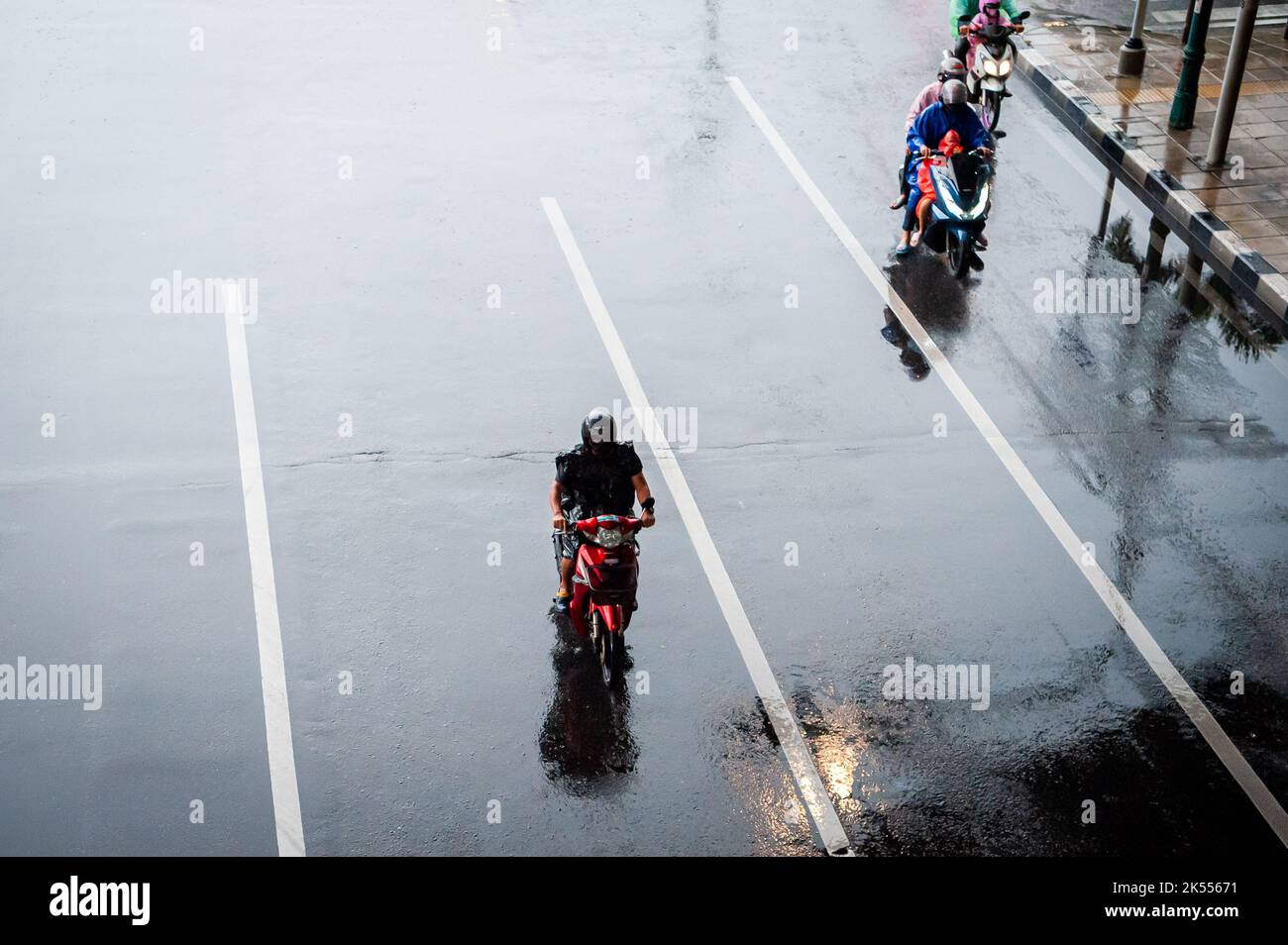 Les voitures, les fourgonnettes, les bus et les motos passent tous le long d'une intersection très fréquentée lors d'une journée sombre et pluvieuse à Bangkok, en Thaïlande. Banque D'Images