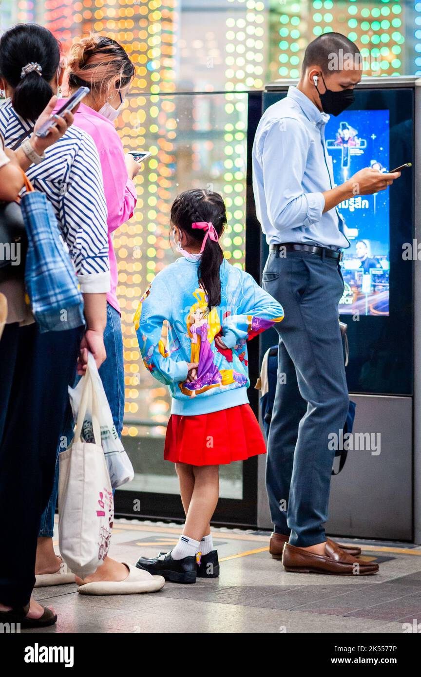 Une adorable fille thaïlandaise se tient sur la plate-forme du train aérien BTS de Bangkok portant son pull Disney. Banque D'Images