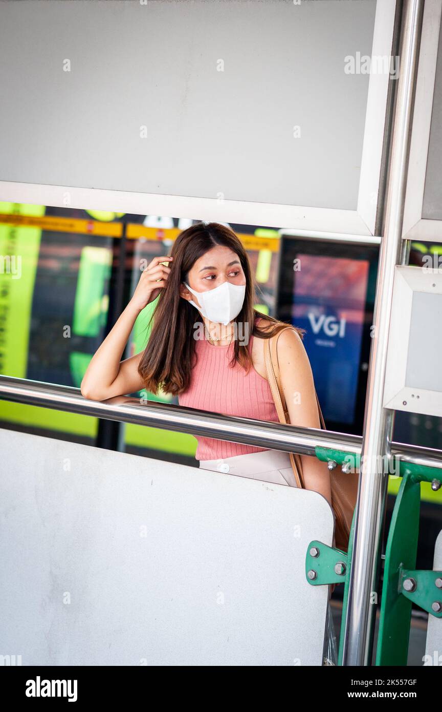 Une fille thaïlandaise élégante perdue dans ses pensées attend son train à une gare de train aérien BTS de Bangkok. Banque D'Images