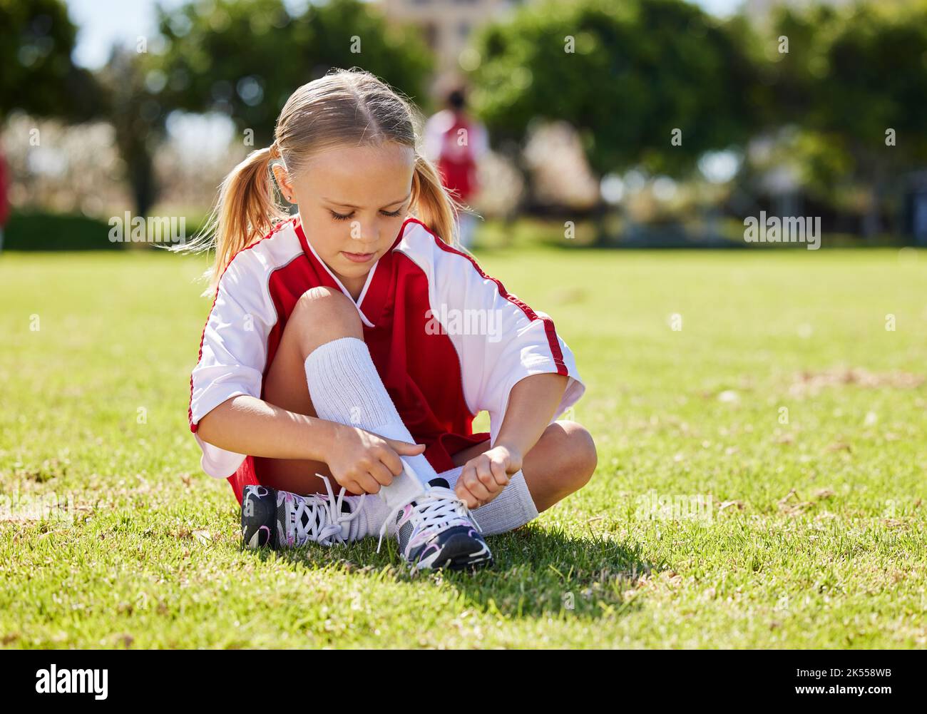 Sports, fille et joueur de football avec enfant sur l'herbe avant le jeu en plein air et l'exercice. Enfants, fitness et chaussures pendant l'entraînement de football, se préparer Banque D'Images