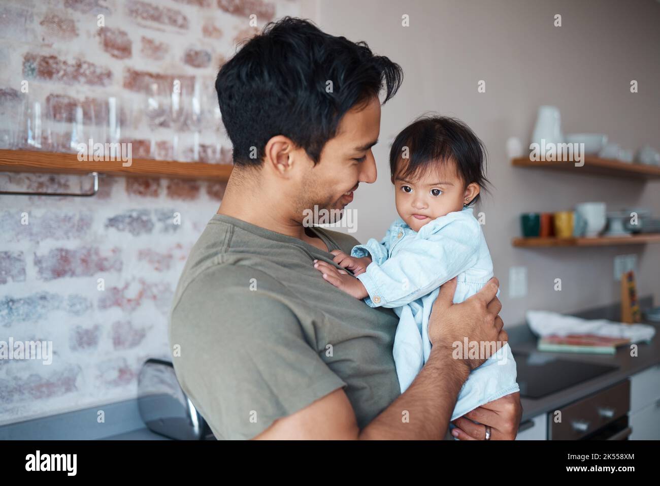 Syndrome de Down, l'amour et le père avec le sourire pour bébé dans la cuisine de leur maison ensemble. Jeune enfant ayant un handicap de développement et des besoins spéciaux Banque D'Images