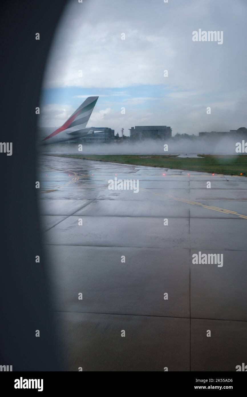 Vue à travers une fenêtre d'avion à avec la pluie traversant le portail, à la vue de la piste et jour humide dehors. Banque D'Images