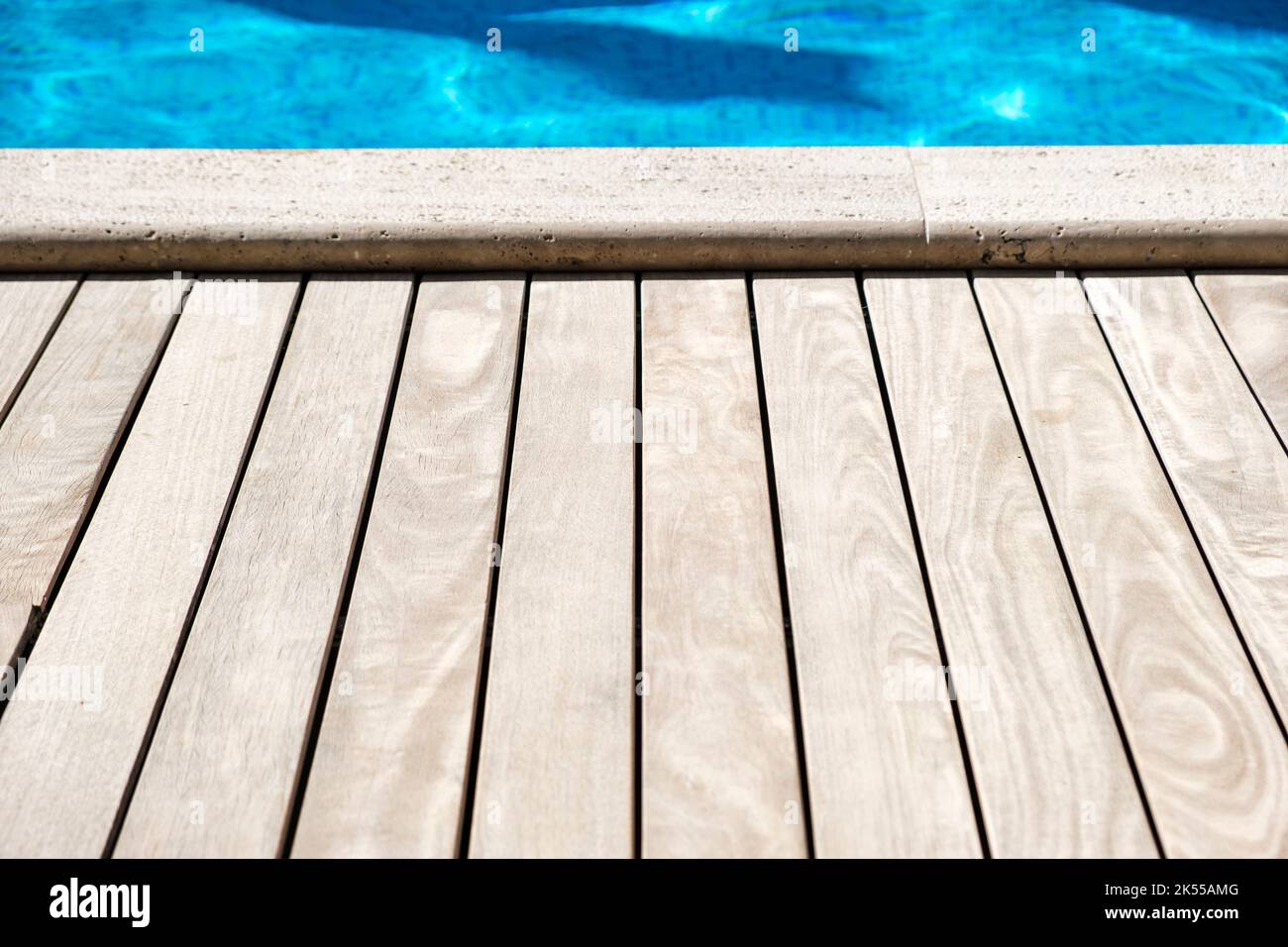 Planches de bois sur le côté d'une piscine bleu profond. Banque D'Images
