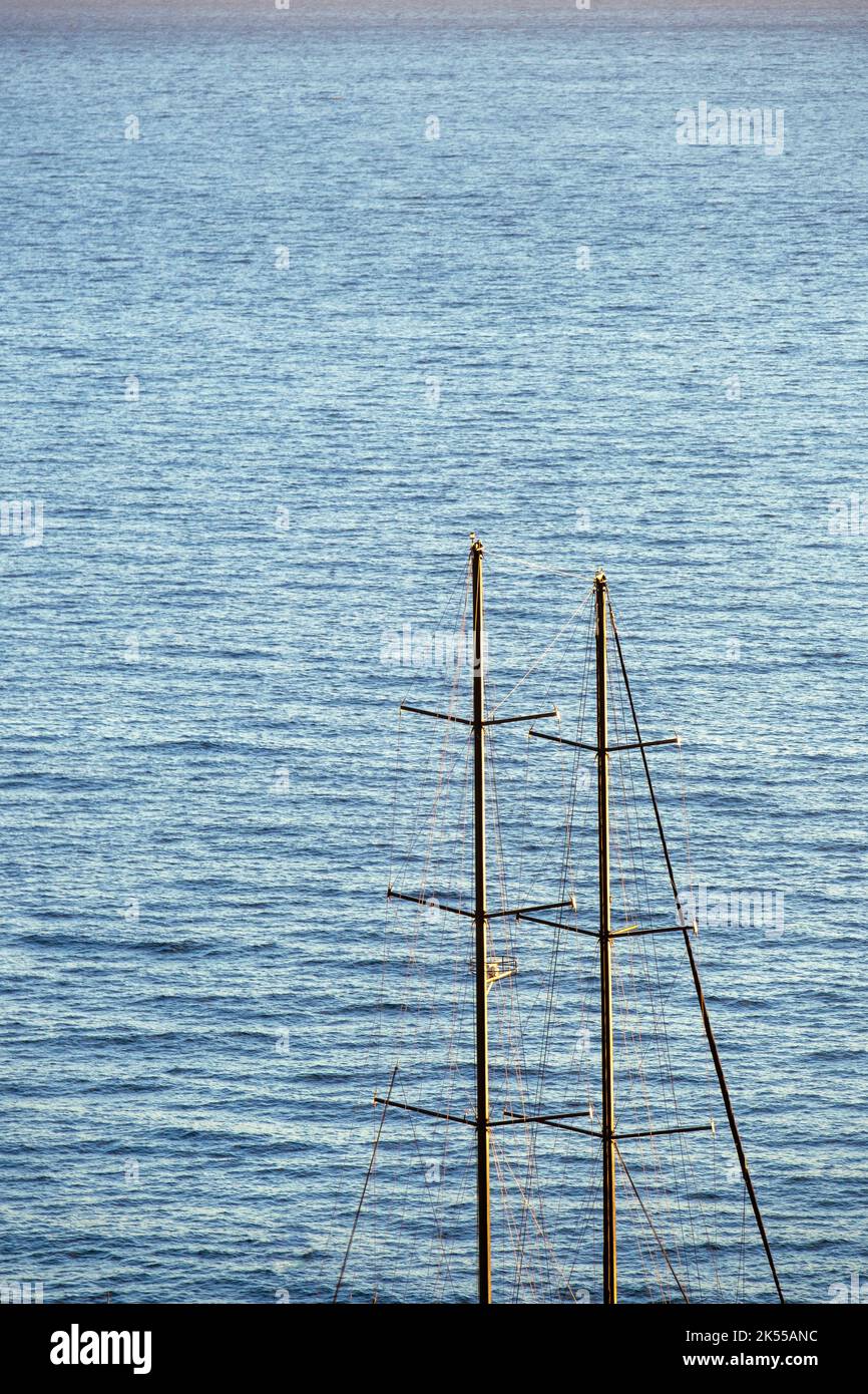 Un voilier avec des mâts mis contre une mer bleu profond. Banque D'Images