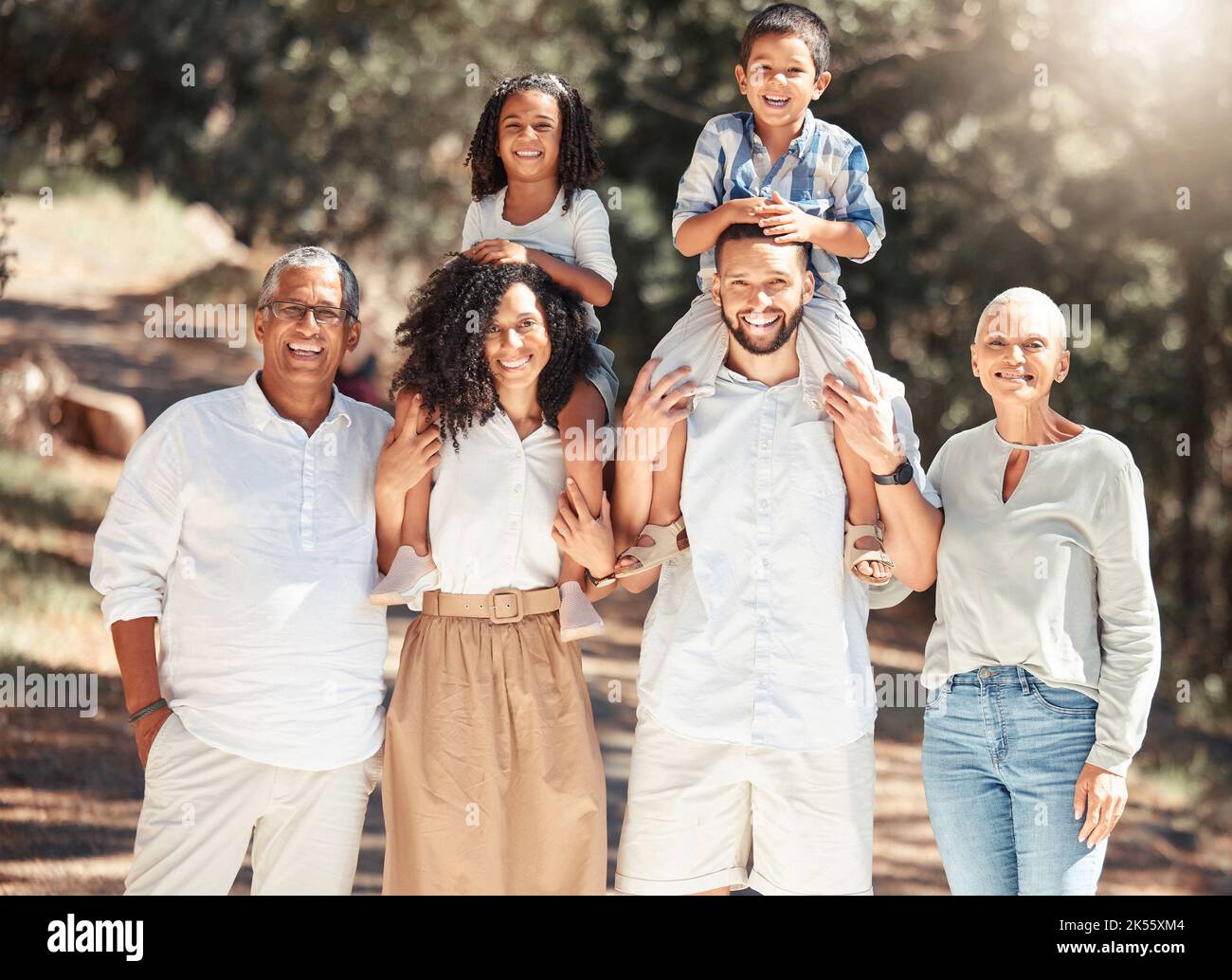 Famille, marcher et sourire ensemble dans la nature, les arbres et le soleil pendant les vacances. Maman, papa et grands-parents marchant avec les enfants dans la forêt, le champ ou le parc Banque D'Images