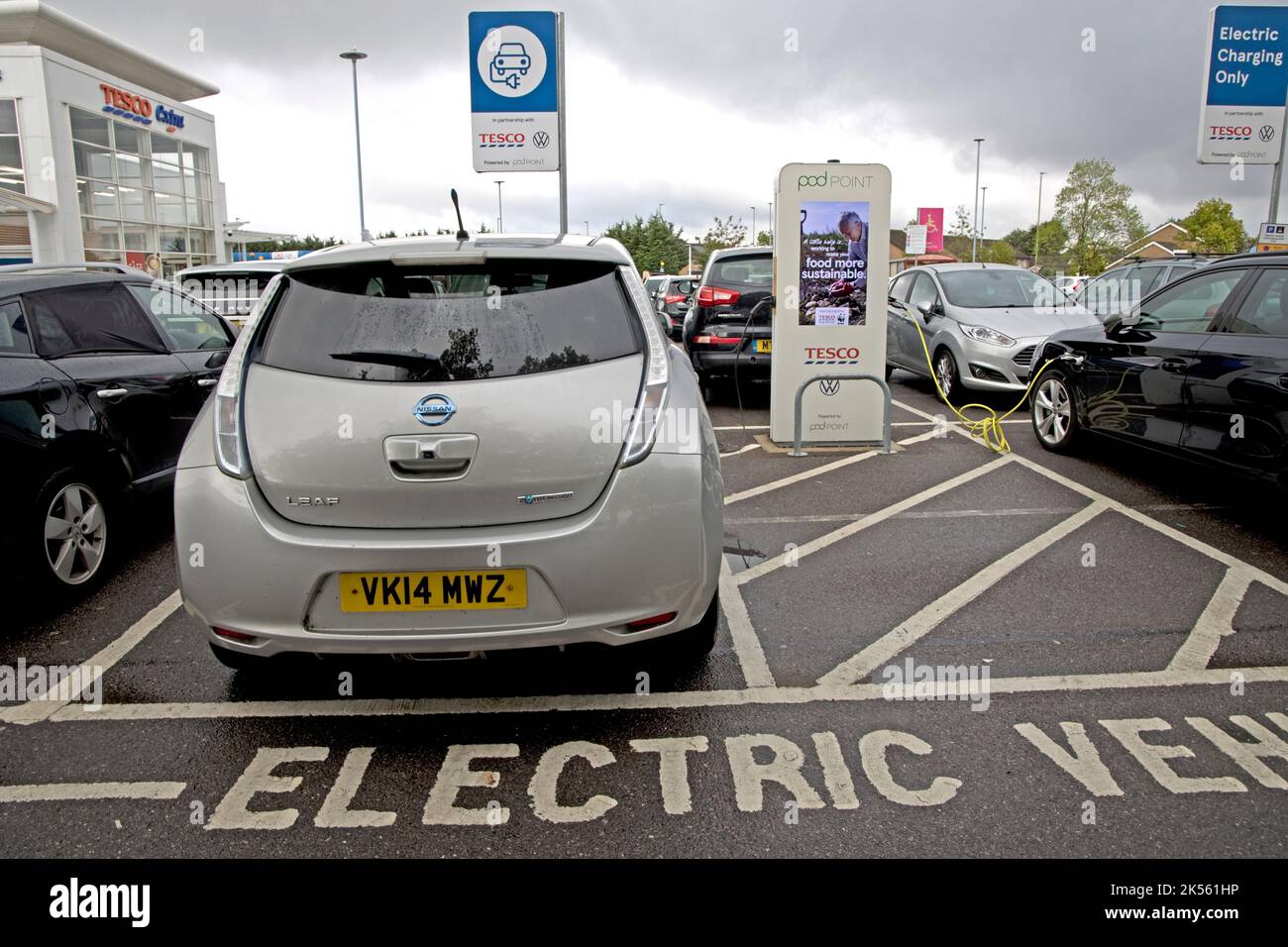 Deux véhicules électriques se chargeant aux points de recharge gratuits de Tesco utilisant 100 % d'électricité renouvelable à Quedgely Gloucester, Royaume-Uni Banque D'Images