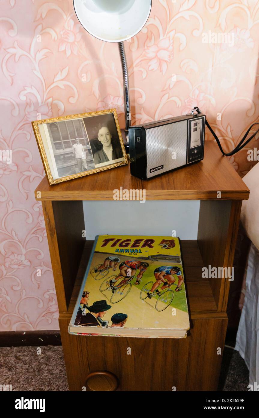 Une vieille table de chevet avec des photos de famille, une ancienne radio à transistor, et une copie du Tiger annuel de 1959. Banque D'Images