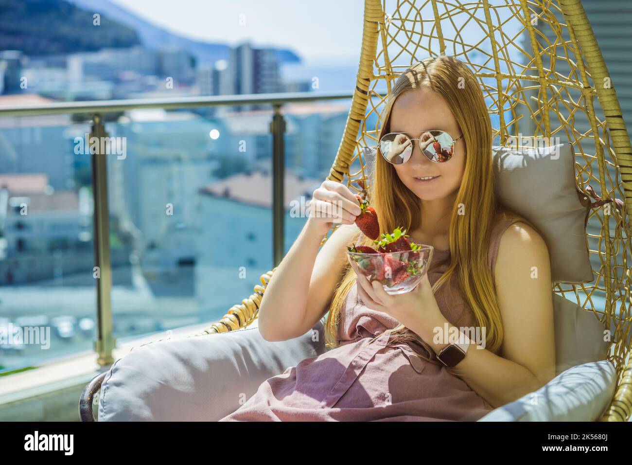 Portrait d'une femme magnifique portant une belle robe assise dans un patio et mangeant de la fraise Banque D'Images