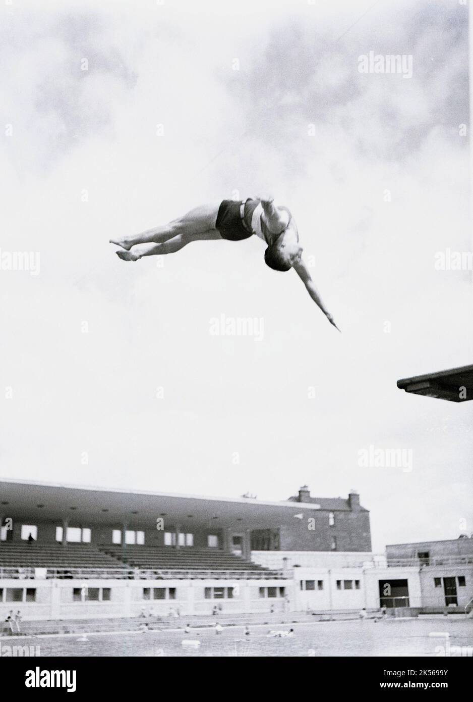 1940s, historique, à l'extérieur d'une piscine en plein air, un plongeur mâle en plein air faisant une plongée de torsion à partir de la planche ou plate-forme de plongée, Angleterre, Royaume-Uni. Banque D'Images