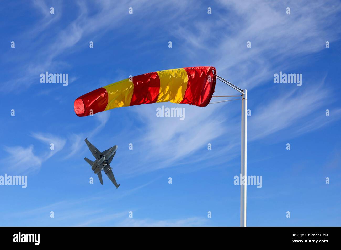 Bonnette à vent rayée jaune et rouge ou cône vent contre un ciel magnifique avec un décollage de jet. Banque D'Images
