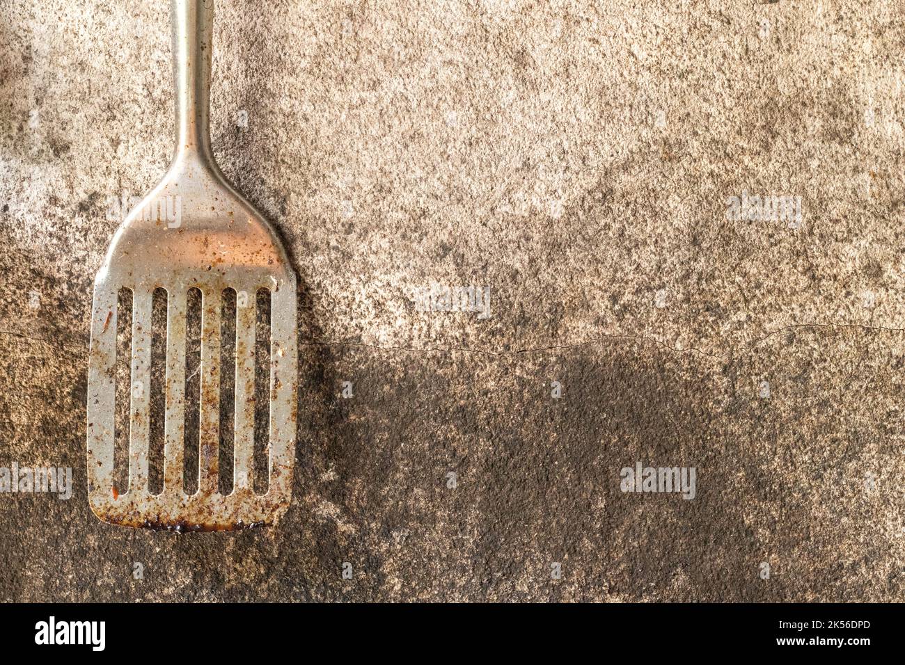 Vieille spatule à poisson rouillée et corrodée sur fond de mur sale. Banque D'Images