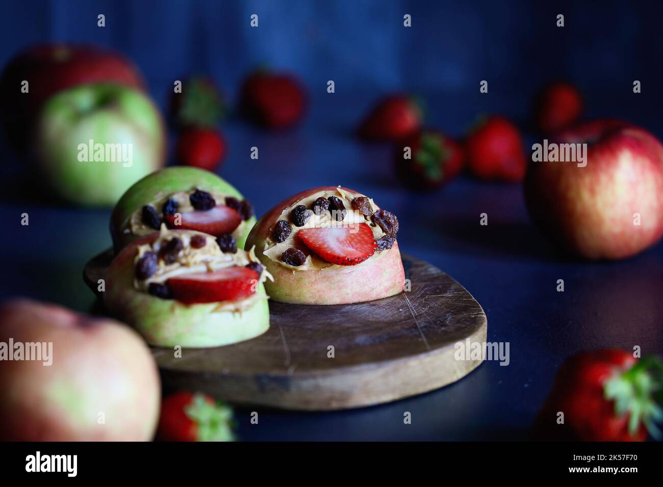 Les mouths de monstre de pomme s'ouvrent large avec des languettes de fraise et des dents de raisins secs. Rempli de beurre d'arachide. Mise au point sélective avec arrière-plan flou. Banque D'Images