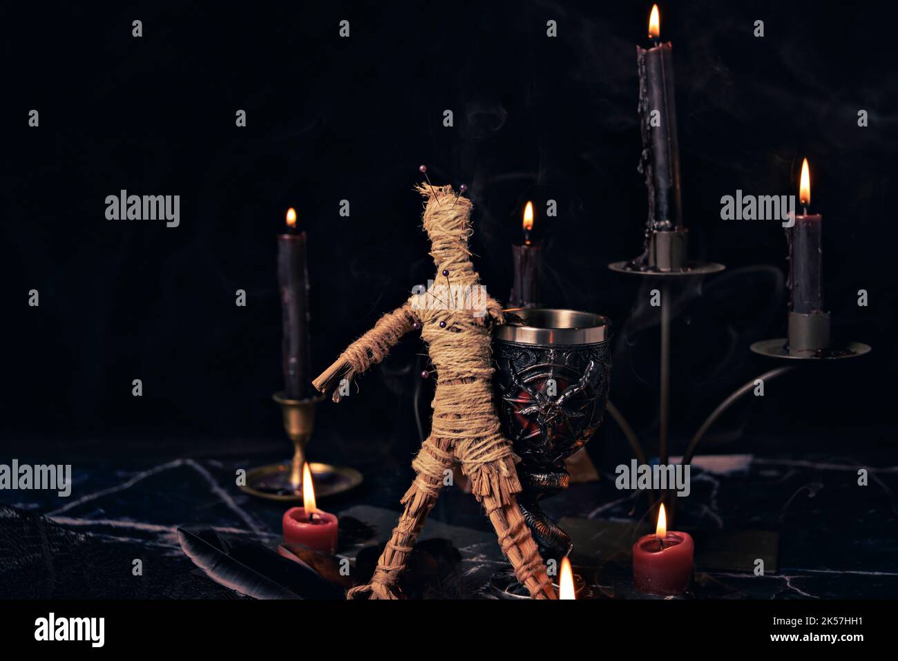 Voodoo Magic concept. Poupée Voodoo clouée avec des aiguilles avec un coeur de chiffon percé sur le pentagramme et autour des bougies en feu. Magique effrayant ou sinistre Banque D'Images