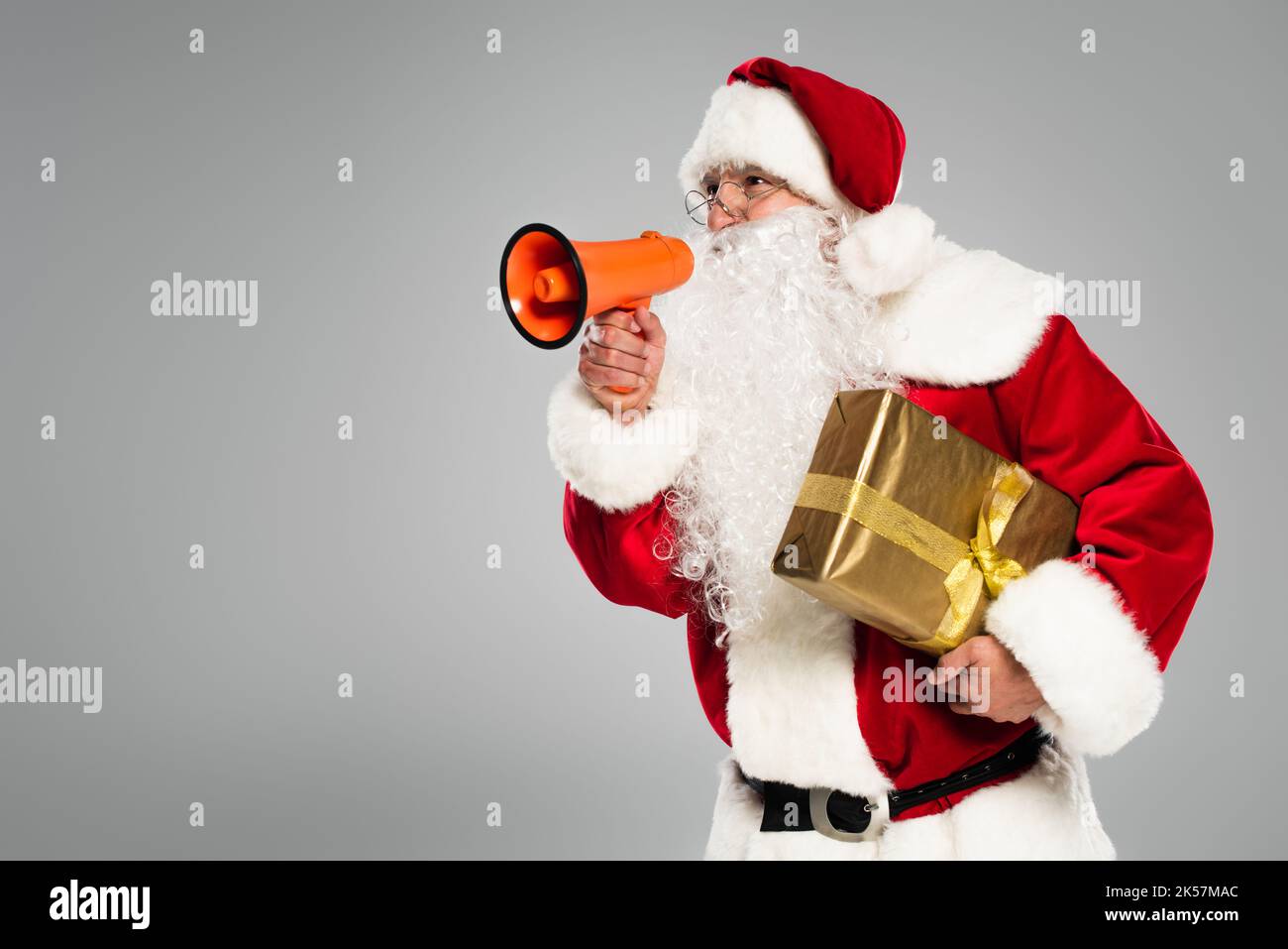 Le Père noël en lunettes tenant le haut-parleur et présent isolé sur image grise Banque D'Images