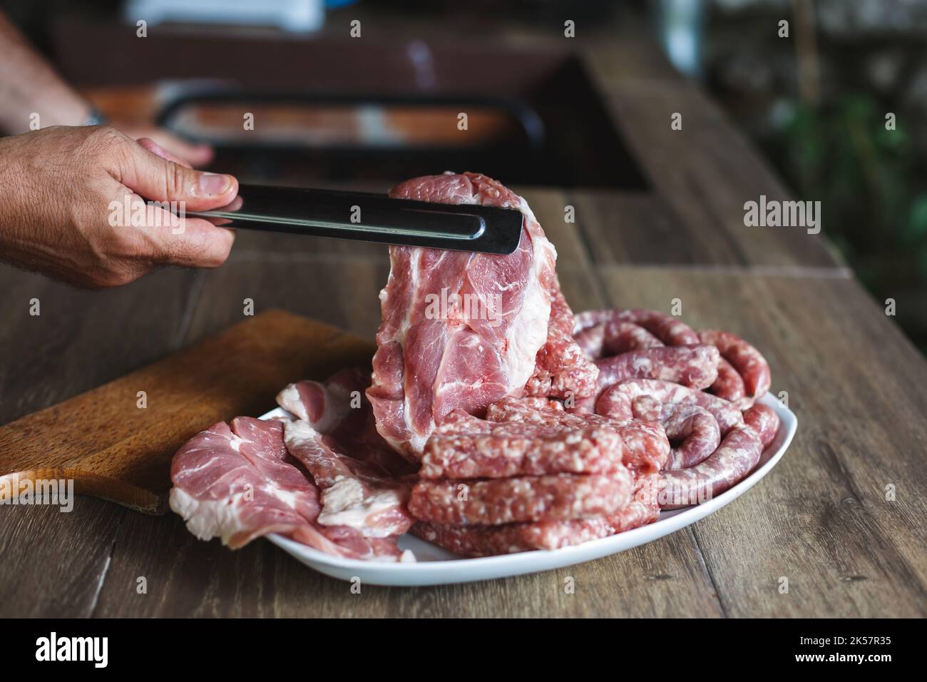 Homme préparant le dîner avec de la viande fraîche, gros plan. Mains tenant le steak de filet cru à l'extérieur. Prêt pour le barbecue. Mise au point sélective, espace de copie Banque D'Images