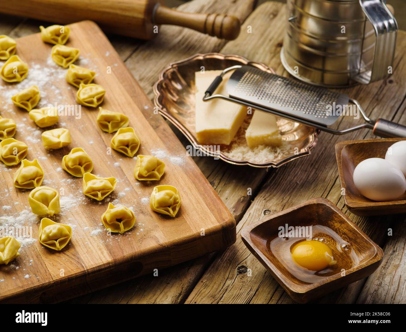 Boulettes faites maison sur une planche en bois, ingrédients, ustensiles de cuisine sur une table de cuisine en bois. Le processus de fabrication de boulettes maison, raviolis. Fama Banque D'Images