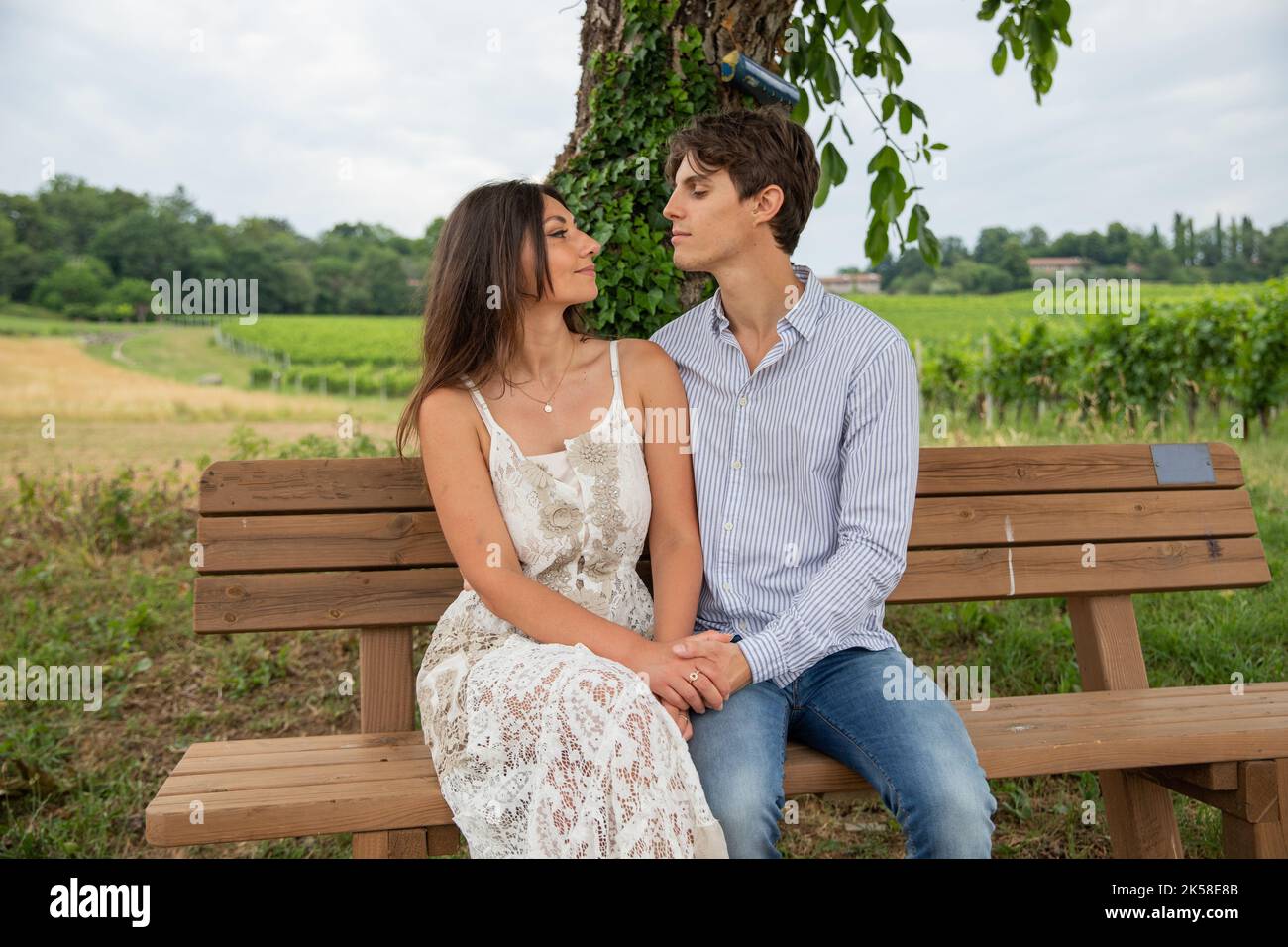 Deux amoureux regardent tendinement dans les yeux de l'autre tout en étant assis sur le banc pendant une promenade dans la campagne. Banque D'Images