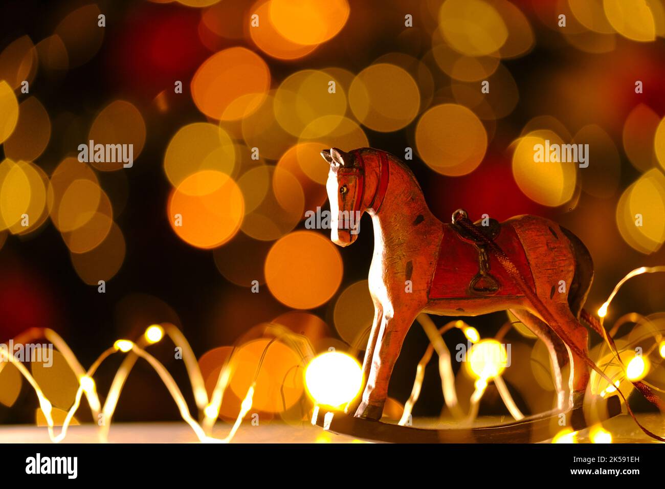 Arrière-plan de Noël et du nouvel an. Cheval en bois sur fond de guirlandes brillantes.décor de Noël dans des couleurs chaudes.ambiance festive. Jouets d'arbre de Noël Banque D'Images