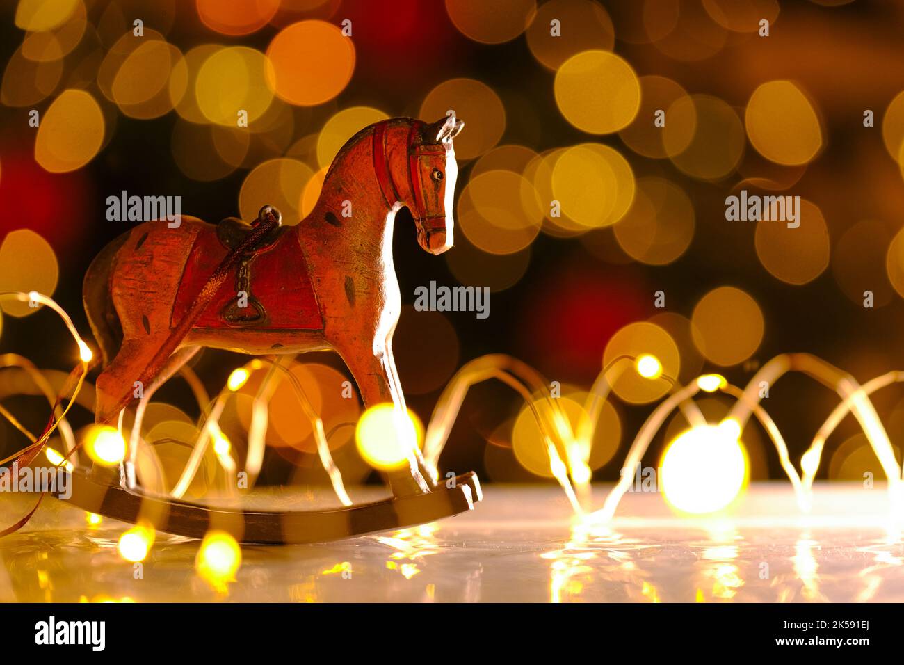 Arrière-plan de Noël. Cheval en bois sur fond de guirlandes brillantes.décor de Noël dans des couleurs chaudes.ambiance festive. Jouets pour arbres de Noël de style vintage Banque D'Images