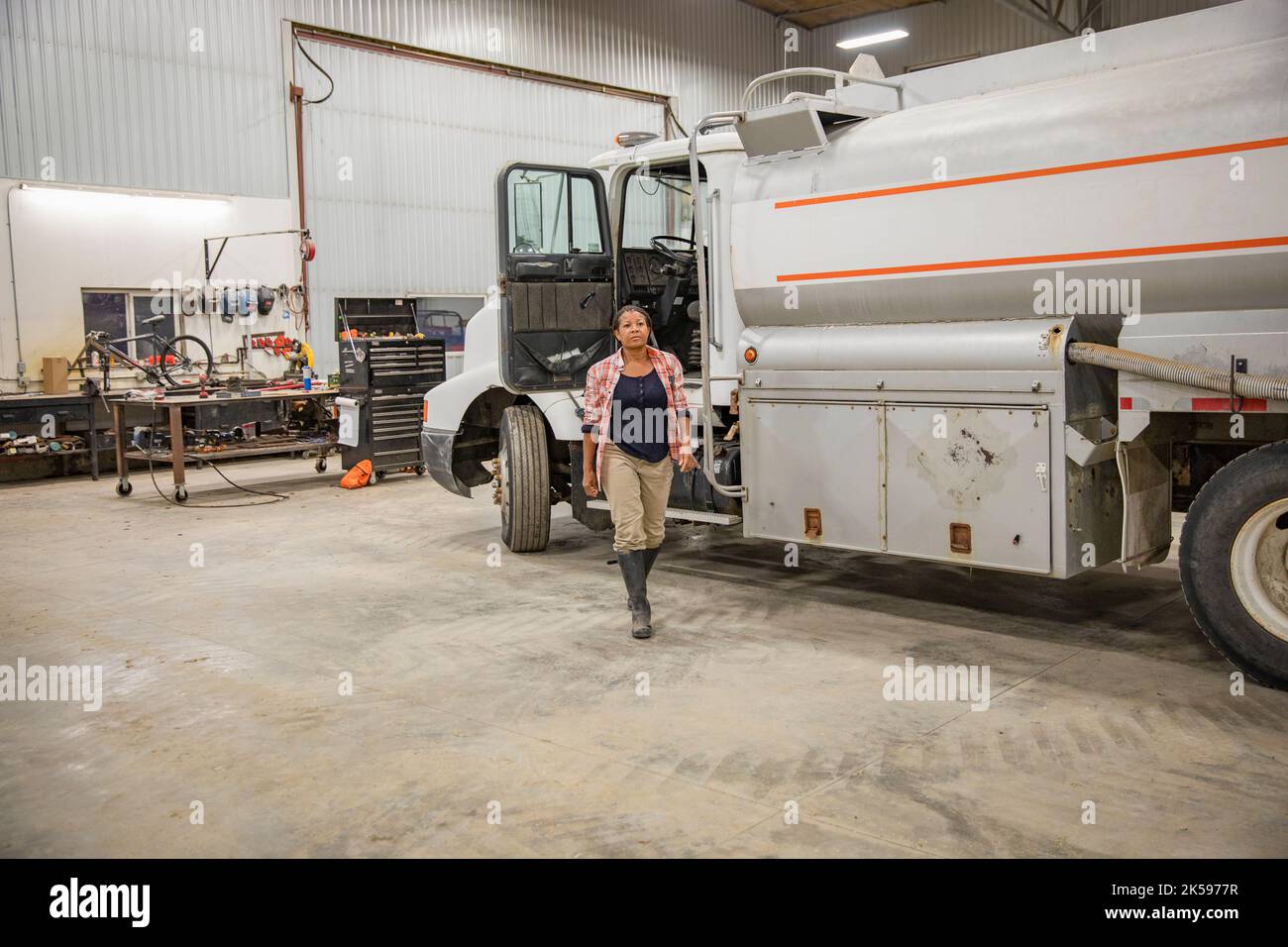 Une agricultrice s'éloigne du camion à l'intérieur de la grange Banque D'Images