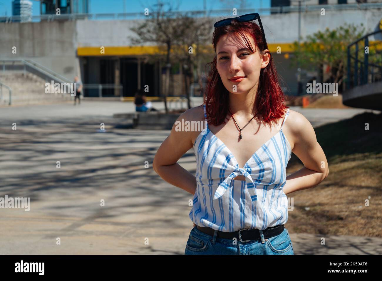 Un portrait horizontal d'une jeune femme attirante aux cheveux rouges avec une expression satisfaite, ses mains sur ses hanches. Banque D'Images