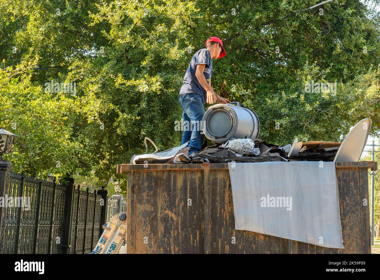 LA NOUVELLE-ORLÉANS, LA, USA - 6 OCTOBRE 2022: Ouvrier de réparation de toit vidant les vieux matériaux de couverture dans la benne à ordures Banque D'Images