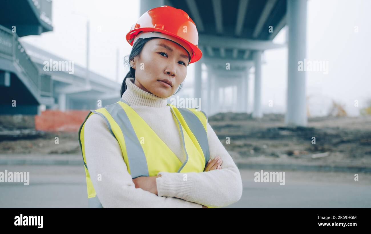 Portrait d'une femme ingénieur de construction asiatique se tenant dans la zone de construction avec les bras croisés et regardant la caméra se sentant confiant dans le travail Banque D'Images