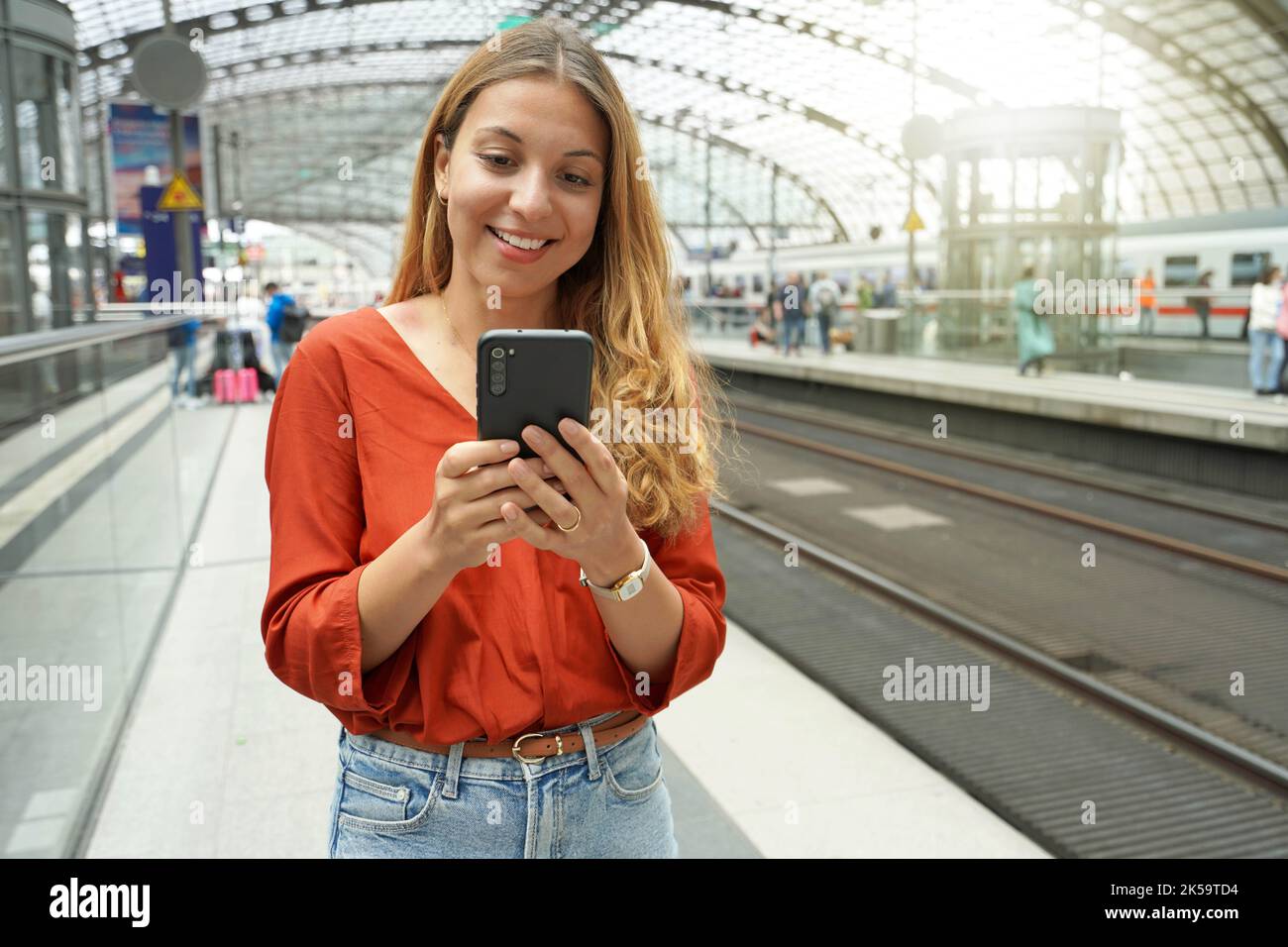 Un voyageur brésilien souriant et attrayant achète un billet en ligne avec un smartphone à la gare. Copier l'espace. Banque D'Images
