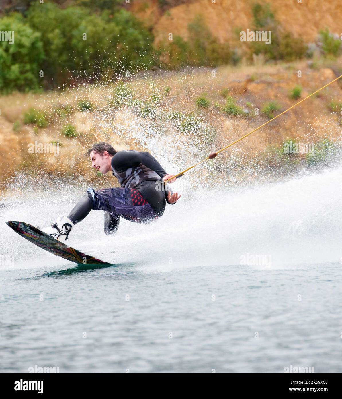 HES un esprit aventureux. Jeune sportif qui fait du wakeboard sur le lac. Banque D'Images