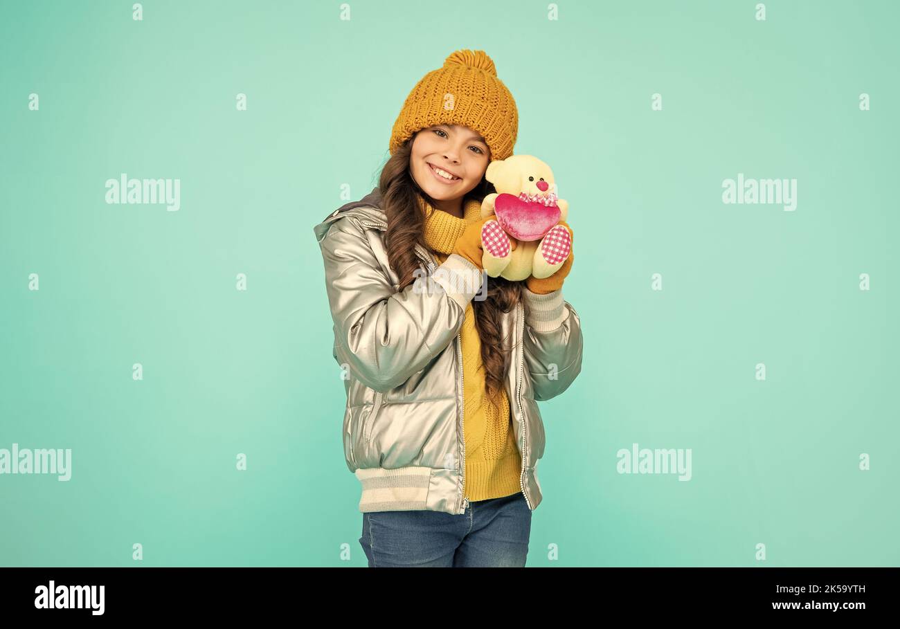 joyeux adolescent fille en vêtements d'hiver tenir le jouet sur fond bleu, jour de la saint valentin Banque D'Images