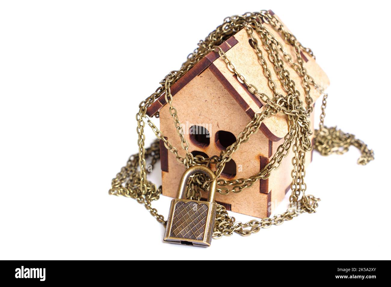 Maison en bois enveloppée de chaînes fixées avec un cadenas sur blanc. Banque D'Images