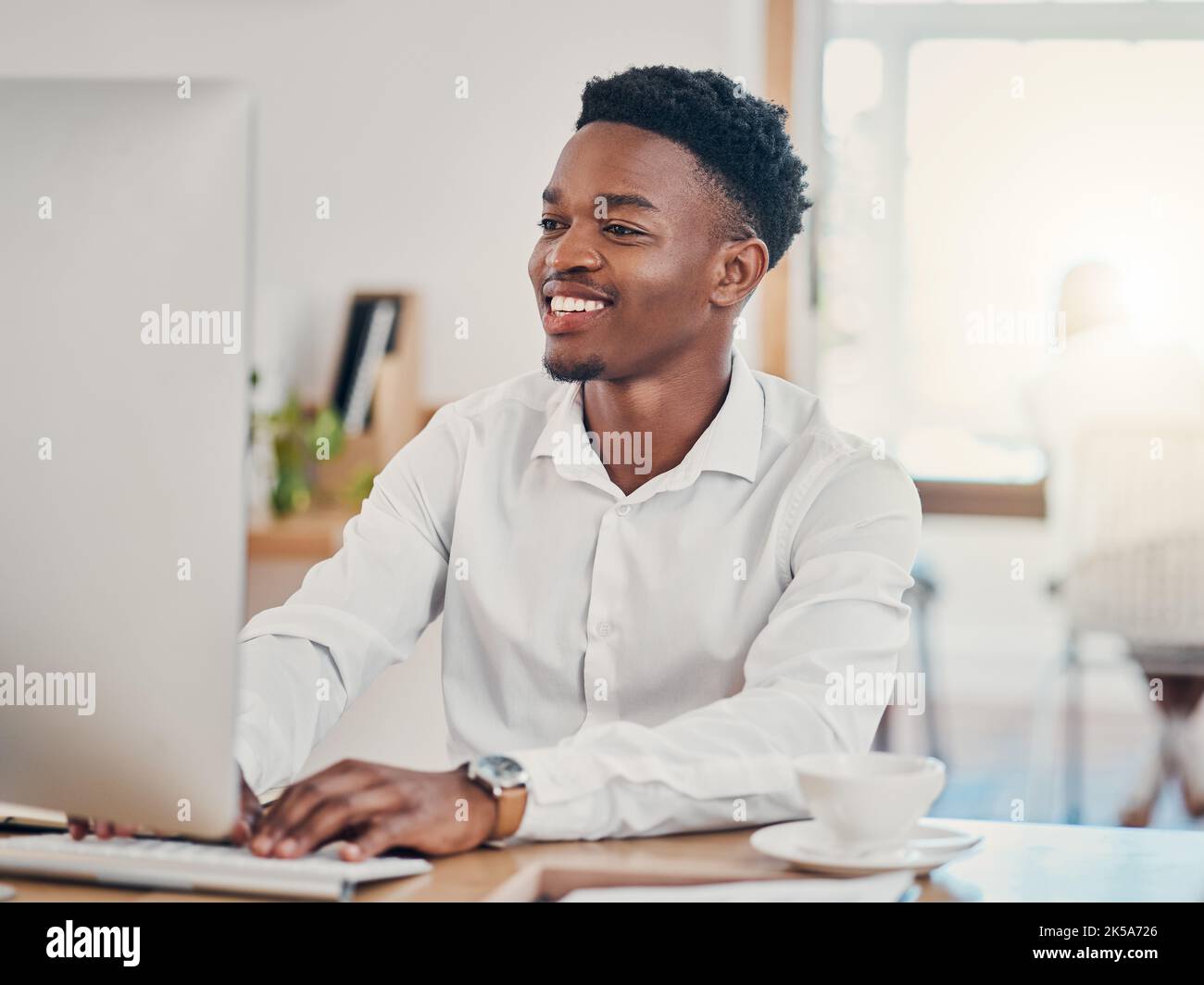 Ordinateur, dactylographie et homme noir travaillant au bureau, faisant des recherches et écrivant des e-mails. Technologie, travail et homme d'affaires avec le sourire Banque D'Images
