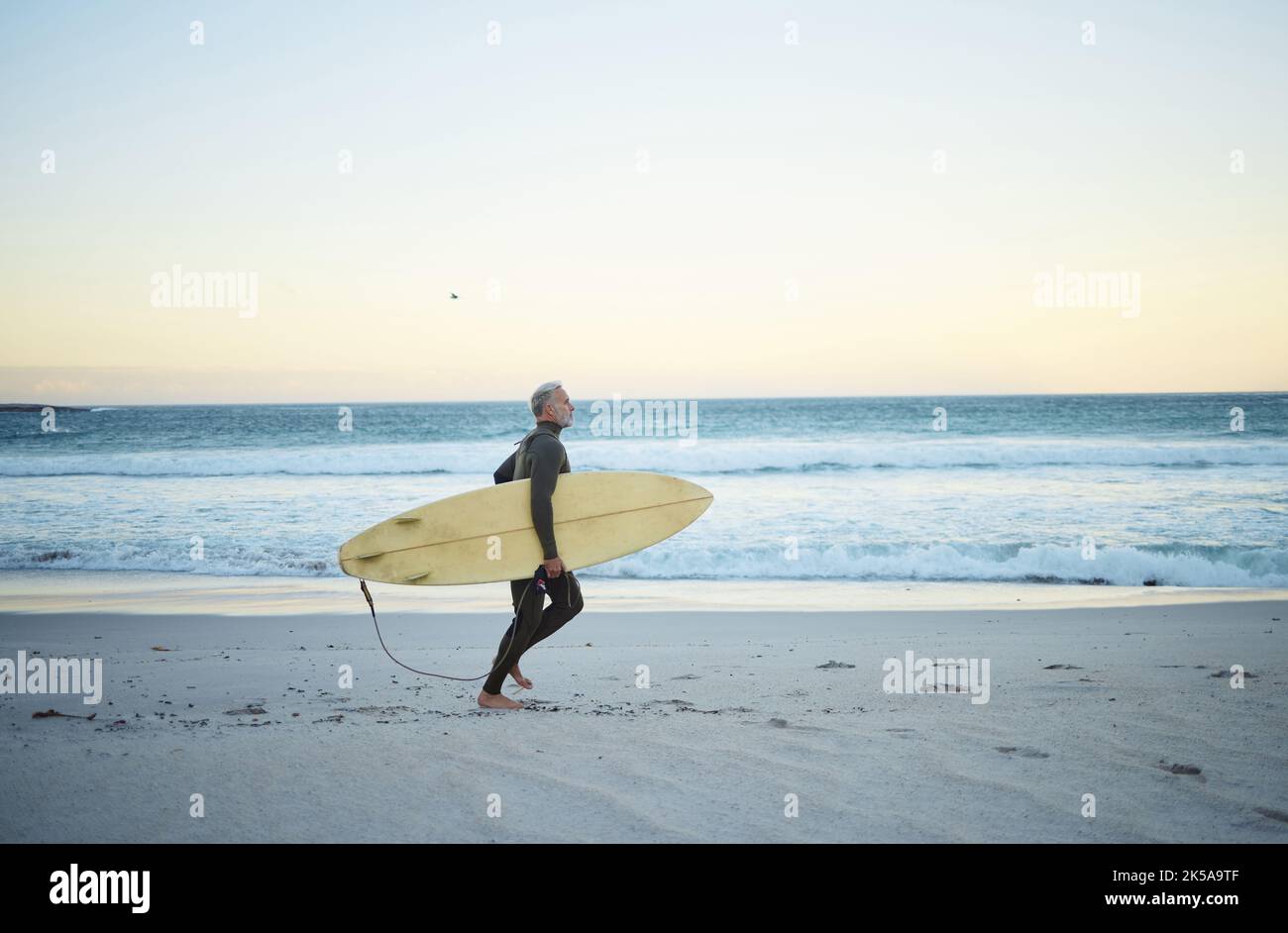 Plage, eau et surf d'un homme sur le sable avec surf marche sur la côte de l'océan le matin à l'extérieur. Surfeur masculin en planche à voile au Costa Banque D'Images