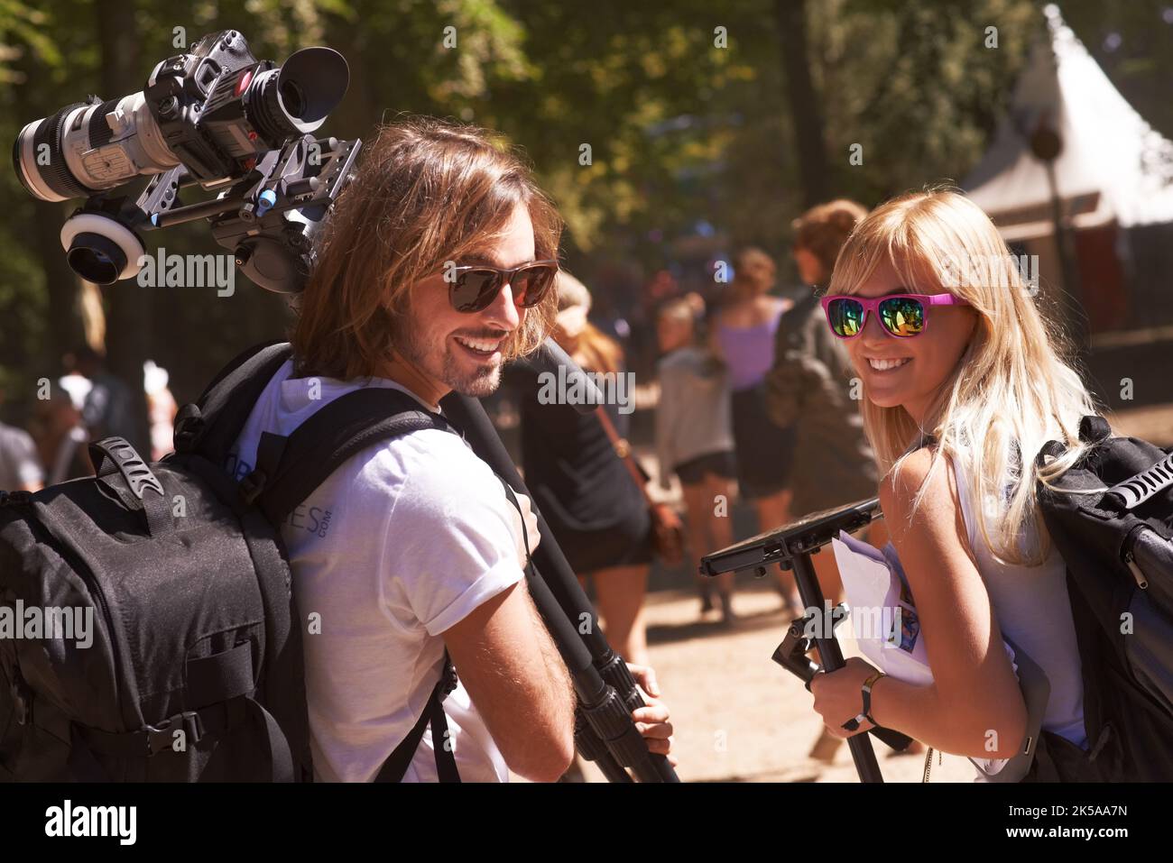 Les photographes du Festival au travail. Vue arrière de deux photographes souriants regardant leurs épaules et marchant avec l'équipement dans leurs mains. Banque D'Images