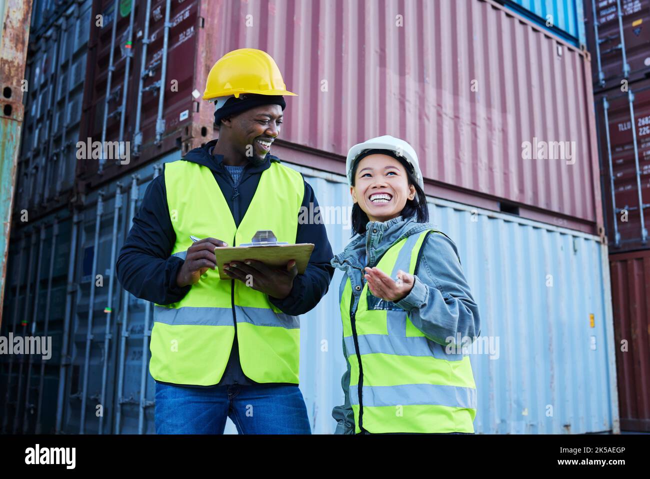L'entrepôt, la direction et le stock de marchandises avec l'homme et la femme discutent de la liste de contrôle et rire à l'usine. Logistique, expédition et collègues de travail Banque D'Images